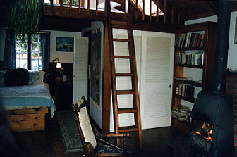 Interior photograph showing fireplace, downstairs bed, and loft